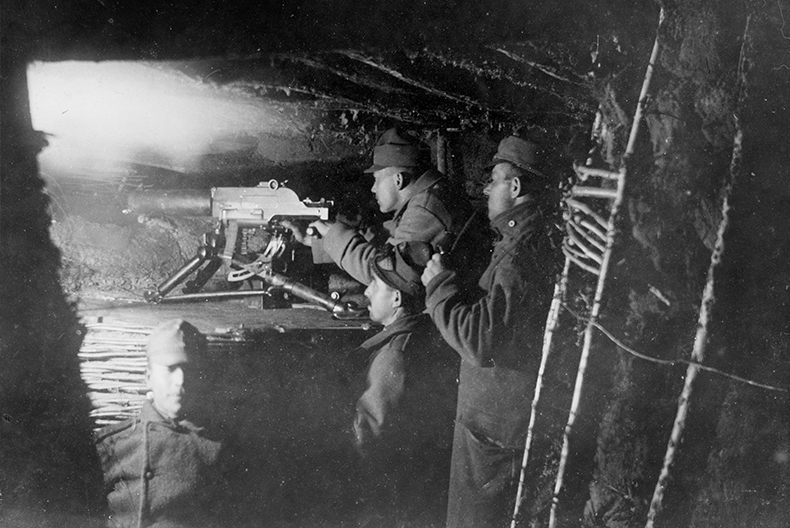 Fyra soldater i en skyttegrav, varav tre av dem st&aring;r bakom en kulspruta och tittar bort&aring;t.