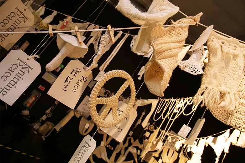 Tv&auml;ttlinor h&auml;nger hit och dit med diverse f&ouml;rem&aring;l stickade i vitt garn. H&auml;r h&auml;nger &auml;ven n&aring;gra papperslappar med bland annat texten "Knitting peace".