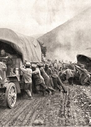 Svartvit bild av en stor folkmassa som hj&auml;lper tv&aring; lastbilar upp p&aring; v&auml;gen igen. V&auml;gen &auml;r lerig och den ena lastbilen verkar ha problem att komma upp ur ett dike.