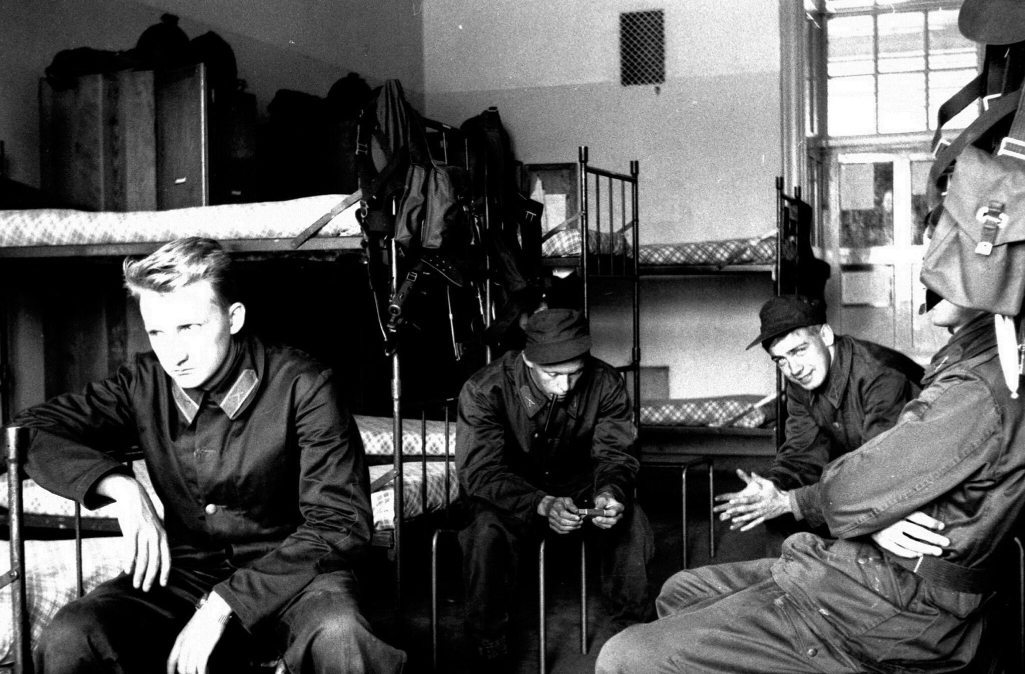 Fyra v&auml;rnpliktiga har en stunds paus och sitter i sitt sovrum d&auml;r v&aring;ningss&auml;ngarna st&aring;r p&aring; rad.