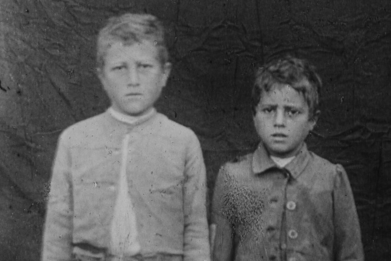 Svartvit bild av tv&aring; barn med bekymrade miner tittar in i kameran.