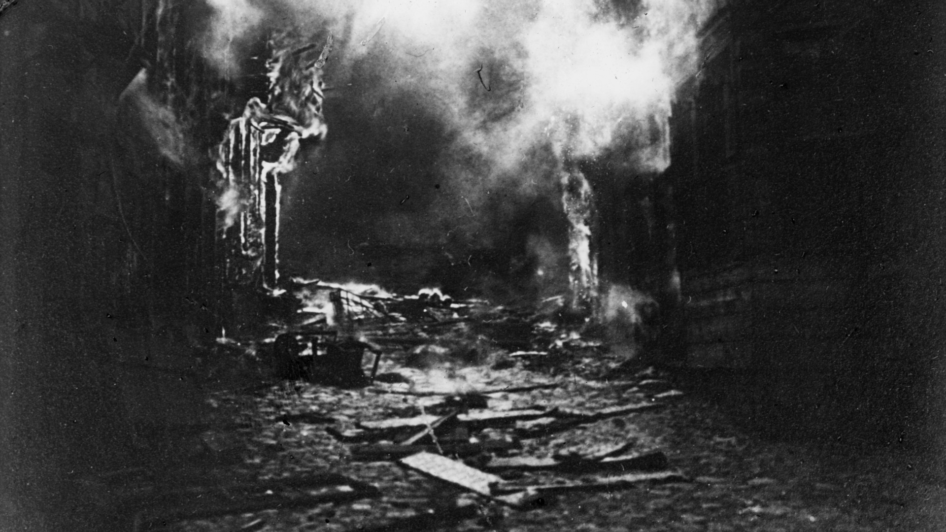 En svartvit bild av f&ouml;rst&ouml;relse. R&ouml;k stiger upp fr&aring;n vad som tidigare var byggnader.