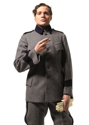 En person ikl&auml;dd gr&aring; uniform, med vita handskar i ena handen och en cigarett i den andra, tittar rakt in i kameran.