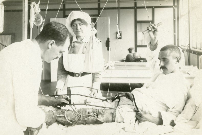 En l&auml;kare unders&ouml;ker benet p&aring; en patient i en sjukhussal. Bredvid st&aring;r en sk&ouml;terska.