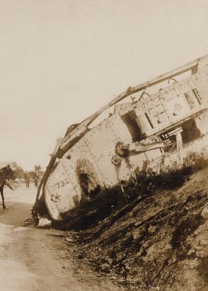 En stridsvagn har fastnat i terr&auml;ngen, en h&auml;st med vagn med tv&aring; passagerare passerar den p&aring; v&auml;gen bredvid.