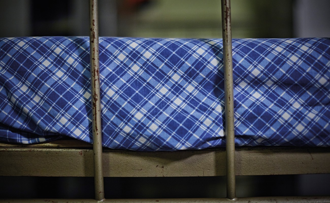 Del av en v&aring;ningss&auml;ng i j&auml;rn fr&aring;n lumpen, med bl&aring;vitrutiga, v&auml;lstr&auml;ckta lakan.