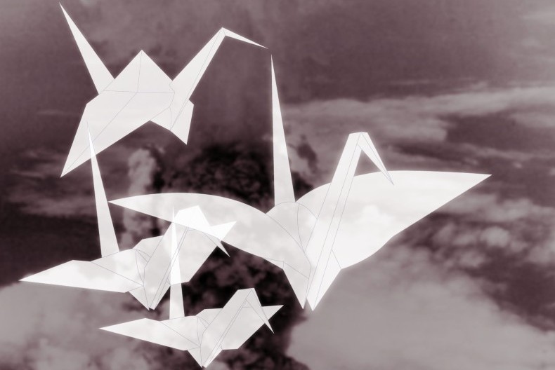Fyra vita origamitranor flyger &ouml;ver ett svartvitt landskap.