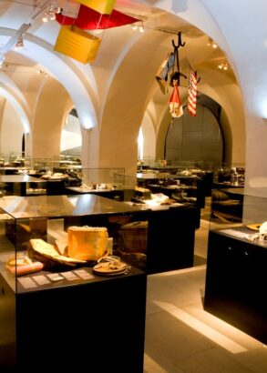 En utst&auml;llningshall med valv i taket och flera glasmontrar fyllda med diverse f&ouml;rem&aring;l.