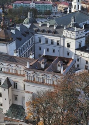 En bild ovanifr&aring;n &ouml;ver ett vitt slott med svart tak, tinnar och torn, slottet i Vilnius. Runtom &auml;r det lummigtl&auml;ngre bort syns andra byggnader.