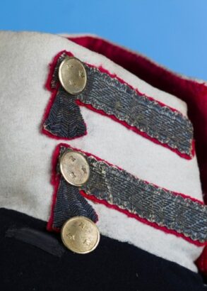 En vit krage p&aring; en m&ouml;rk uniform, den &auml;r dekorerad med knappar och kragspeglar.