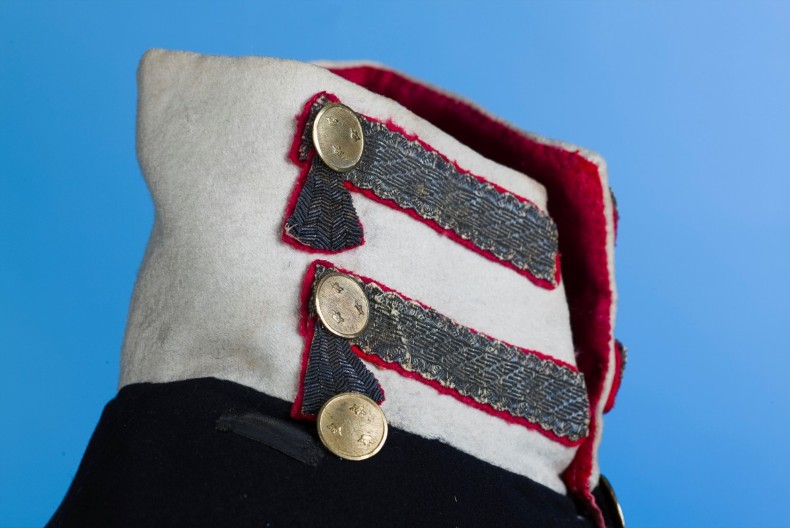 En vit krage p&aring; en m&ouml;rk uniform, den &auml;r dekorerad med knappar och kragspeglar.