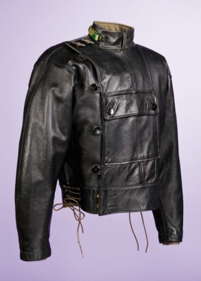 En uniformsliknande svart skinnjacka, mot lila bakgrund.